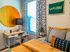Bright and inviting bedroom with a modern desk, striking geometric wall art, and cozy textured bedding, perfect for relaxation and inspiration.