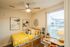 Charming bedroom with vibrant yellow bedding, modern decor, and natural light through a large window.