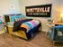 Charming bedroom with vibrant decor, featuring a colorful bedspread, creative wall art, and a cozy work desk.