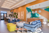 Chic and vibrant lounge area with stylish blue seating, bright yellow stools, and bold geometric wall designs, perfect for socializing and relaxation.
