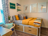 Cozy bedroom adorned with vibrant decor, featuring a stylish bed with storage drawers, modern art, and abundant natural light.