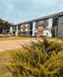 Modern apartment complex with stylish facade, lush landscaping, and recreational volleyball court.