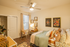 Cozy bedroom with stylish decor, featuring floral wall art, a comfortable bed with colorful cushions, and a functional desk space, bathed in warm natural light.