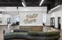 Modern apartment lobby with stylish decor, featuring a chic 'Hello There' wall art and a curved green sofa.
