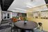 Modern communal area with stylish decor, featuring vibrant orange and green seating, a sleek black table, and contemporary design accents for a welcoming atmosphere.