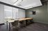 Modern meeting room featuring a sleek wooden conference table, stylish chairs, and a flat-screen TV, with a bright window view of greenery.