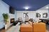 Elegant apartment living room with a cozy fireplace, modern orange sectional sofa, vibrant artwork, and a sleek pool table.