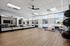 Spacious, modern fitness studio with floor-to-ceiling mirrors and natural light, featuring Pilates equipment and exercise balls.