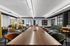 Modern communal workspace featuring sleek wooden tables, colorful chairs, and stylish decor in a well-lit environment.