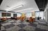 Modern office space featuring stylish orange chairs, sleek meeting tables, and large windows providing abundant natural light.