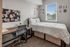 Cozy bedroom with a stylish desk, organized bulletin board, and bright window views.
