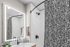 Modern bathroom featuring elegant black and white patterned shower curtain, illuminated mirror, and sleek fixtures for a luxurious touch.