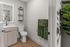 Modern bathroom with sleek vanity, elegant mirror lighting, and lush green towel accents.