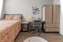 Modern bedroom featuring a cozy bed with artistic decor, sleek wooden workspace, and stylish wardrobe, all on elegant wooden flooring.