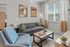 Inviting modern living room featuring a cozy gray sofa, stylish blue chair, and elegant artwork in a bright, airy space.