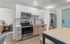 Modern kitchen with sleek cabinets, stainless steel appliances, and a dining area, showcasing a stylish and cozy open concept living space.