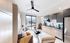 Modern apartment living area featuring a cozy sofa, chic kitchen with stainless steel appliances, and large window with mountain views.