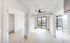 Modern apartment with sleek wooden flooring, abundant natural light from large windows, and a stylish ceiling fan, offering a bright and airy living space.