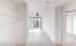 Bright apartment hallway with large window, light wood flooring, and sleek ceiling fan, showcasing modern design and ample natural light.