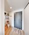 Inviting apartment entryway with a sleek dark door, stylish shelves with decor, and cozy woven baskets on a warm wooden floor.