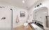 Modern bathroom with sleek black vanity, stylish lighting, and framed artwork. Inviting shower area and elegant decor create a chic ambiance.