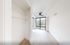 Bright and airy room with large windows, elegant ceiling fan, and modern shelving, offering a serene urban view.