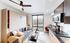 Modern apartment living area with a cozy sofa, sleek kitchen, and large window offering a city view.