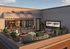 Charming rooftop patio with elegant seating, vibrant plants, and cozy fire pit, perfect for urban relaxation.