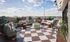 Stunning rooftop terrace featuring stylish seating, a cozy fire pit, and breathtaking city views under a vast blue sky.