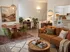 Charming living space with cozy velvet chairs around a wooden dining table, textured sofa, and open kitchen, infused with warm earth tones and abundant natural light.