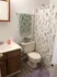Charming bathroom with nature-themed decor, featuring a floral shower curtain, wooden vanity, and soft lavender rug.