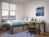 Cozy apartment bedroom with large window view, stylish workspace, and modern storage bed.