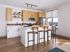 Modern kitchen with sleek wooden cabinets, a spacious island with bar stools, and large windows for natural light.