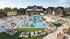 Luxurious outdoor pool area with stylish loungers, vibrant social spaces, and a large screen for entertainment under clear blue skies.