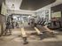 Vibrant gym with modern equipment, wall-mounted TVs, and large windows showcasing a scenic outdoor view.