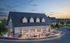 Charming clubhouse with modern design, featuring outdoor seating and lively social gathering at sunset.