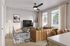 Elegant living room with a modern ceiling fan, stylish leather sofa, colorful cushions, and large windows allowing natural light to brighten the space.