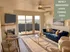 Inviting living room in newly renovated units, featuring a plush blue sofa, elegant coffee table, and a cozy fireplace with stunning balcony views.