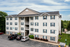 Charming modern apartment building with four stories, ample parking, and lush greenery, perfect for comfortable living.