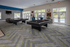Modern recreational room with vibrant floors, featuring billiards tables, plush seating, and expansive windows overlooking the pool.