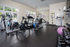 Bright and modern apartment gym with cardio machines, weights, and yoga equipment, offering a pristine workout environment.