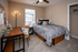 Cozy and contemporary bedroom featuring a stylish bed with decorative pillows, a modern desk, and ample natural light from a large window with a view. Perfect for comfort and style.
