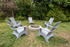 Charming outdoor seating area with modern chairs around a rustic stone fire pit, perfect for cozy gatherings in a lush garden setting.