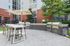Contemporary outdoor area featuring stylish dining set under large umbrella with modern grills, ideal for entertaining.