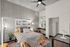 Modern bedroom with stylish decor featuring a cozy bed, ambient lighting, and a workspace by the window, highlighting an open closet and chic concrete walls.