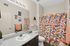 Bright and modern bathroom featuring a vibrant fruit-themed shower curtain, elegant decor, and ample counter space.