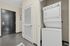Modern apartment entryway featuring a sleek black door and a convenient in-unit stacked washer and dryer.