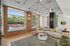 Modern living room with large windows, chic lighting, and a cozy L-shaped couch complemented by stylish decor and natural light.