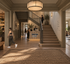 Inviting lobby of Spartan Club, featuring a warm, modern design with a reception desk, stairway, and activity rooms for yoga and Pilates.