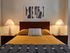 Elegant bedroom with a cozy atmosphere, featuring a wooden headboard, modern art, and soft lighting from stylish table lamps on each side of the bed.
